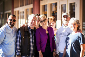 Kyrsten Sinema standing with a group of six other people, in front of store doors.